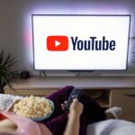 A person watching YouTube on a television with popcorn