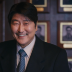 Veteran Korean actor Song Kung-ho plays Park Doo-chill (aka Uncle Samsik) in a dark business suit, smiling in a wood-lined office