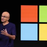 Microsoft CEO Satya Nadella in front of the Windows logo