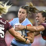 Blues player is tackled by two Maroons in the Women