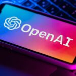 OpenAI logo on phone sitting on top of laptop keyboard