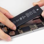 An iPhone with its display removed and battery partially removed