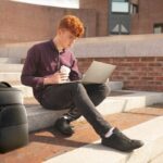 College student sitting on steps with coffee and Dell Laptop