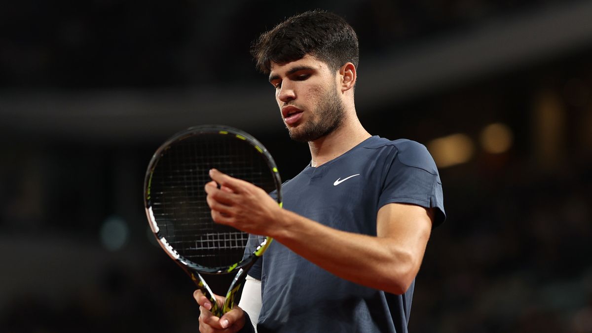 Carlos Alcaraz inspects his racket on-court at the French Open 2024