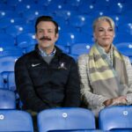 Ted Lasso (Jason Sudeikis) and Rebecca Welton (Hannah Waddingham) sitting in the stands in