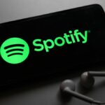 Spotify logo on a smartphone with headphones next to it