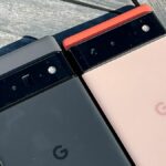 The Google Pixel 6 Pro (in black) and Google Pixel 6 (in coral) laid next to each other on wooden decking