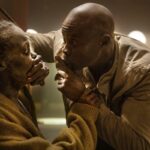 Henri (Djimon Hounsou) covers the mouth of Sam (Lupita Nyong