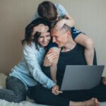 Family looking down at laptop while embracing