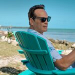 Andrew Yancy (Vince Vaughn) sits on a blue deck chair at the beach in Apple TV Plus