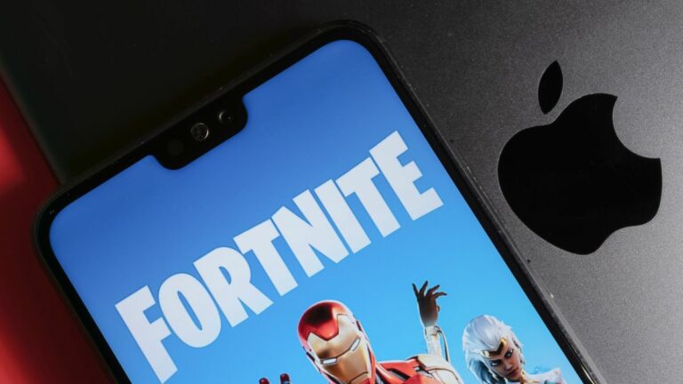 Fortnite running on phone on top of MacBook showing Apple logo