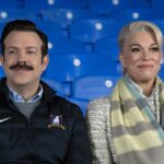 (L, R) Jason Sudeikis as Ted Lasso and Hannah Waddingham as Rebecca Waddingham sit together in the Richmond stands in Ted Lasso season 3 episode 12, &quot;So Long, Farewell&quot;