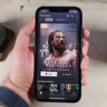 The new-look Netflix app shows a poster for Vikings: Valhalla on an iPhone