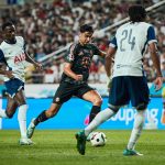 Aleksandar Pavlovic, in black shorts and shirt, dribbles through the Spurs lines in the Tottenham vs Bayern Munich live stream.