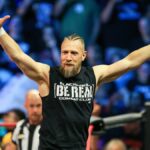 Bryan Danielson in the ring, with his arms in the air, in a black 'Be Real' t-shirt, ahead of AEW All Out 2024.