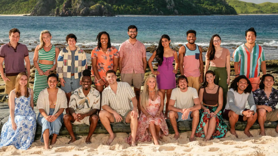 The cast of competitive reality series &quot;Survivor 47&quot; wearing colourful summer clothes pose on an exotic beach with the surf in the background