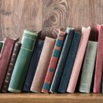 Old books leaning over on a wooden bookshelf