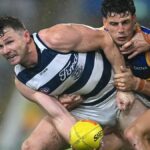 Patrick Dangerfield (L), wearing the Cats black and white striped vest, of the Cats (L) is tackled by Jarrod Berry of the Lions in the Geelong vs Brisbane live stream.