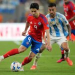 Víctor Davila of Chile, in a red shirt and blue shorts, plays the ball during match against Argentina.