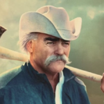 Marty Raney, wearing white western hat and carrying axe over his shoulder, in a still from Homestead Rescue season 12 TV show 2024