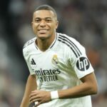 Kylian Mbappe centre-forward of Real Madrid and France, wearing white Real Madrid football kit and smiling broadly, in anticipation of Real Madrid vs Barcelona – the first El Clasico of 2024/25 La Liga season.