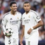 Jude Bellingham (L) and Kylian Mbappe discuss free kick duties during the Champions League, wearing the all white kit of Real Madrid.