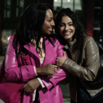 Helen (Alexandra Burke) and Sarah (Mandip Gill) embrace happily on a night out in Curfew