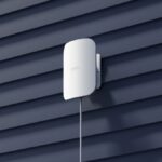 An eero Outdoor 7 mesh extender mounted on a wall in the sun