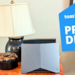 The TP-Link Archer GE800 on a table with a Tom's Guide Price Drop deals badge