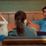 A man (R) and a women (L) sit in Couples Therapy with therapist Orna Guralnik with her back to the camera between them.