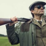 Lord Tony Baddingham (David Tennant) poses with a shotgun over his shoulder in &quot;Rivals&quot;