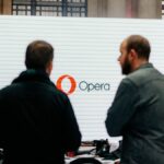 Two Opera Browser Days attendees standing in front of a screen displaying the Opera logo