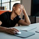 A man looking bored using a desktop computer