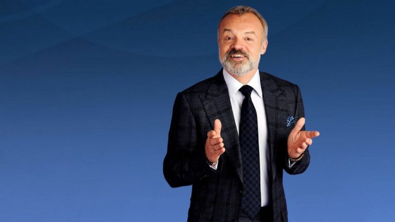 Graham Norton in suit in front of blue background