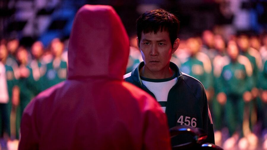 Promotional image of 'Squid Game' season 2 which shows Seong Gi-hun (Lee Jung-jae) standing up to a guard in front of a large group of contestants.